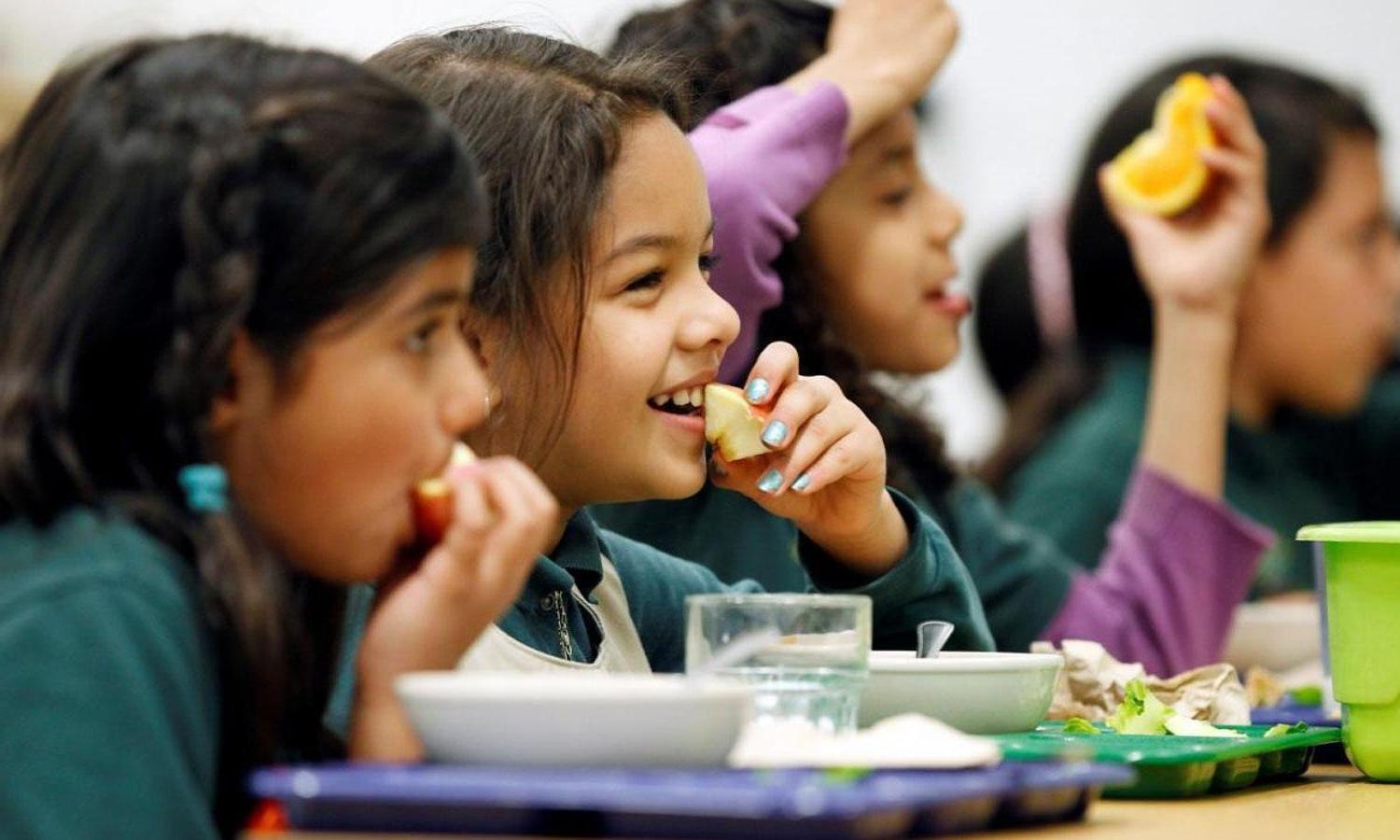 Girls eating fruit in a school cafeteria