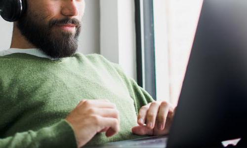 Person wearing headphones sitting in front of a laptop.